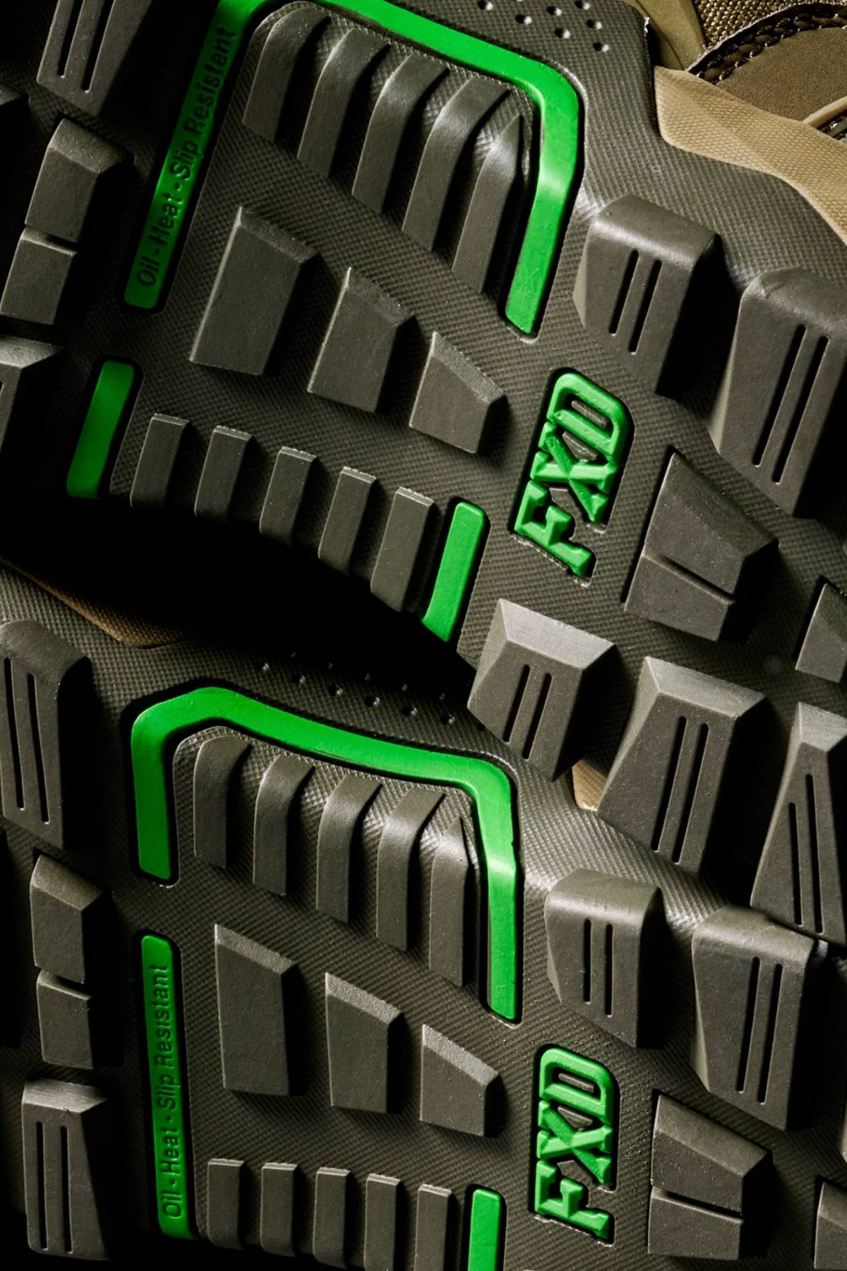 Close-up of the FXD WB-6 Work Boot’s rugged black soles with bold green accents and "FXD" molded into the tread. Deep grooves and angular shapes provide traction, meeting high safety standards.