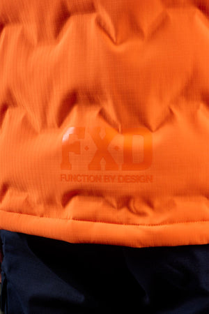 Close-up of the FXD WO-6 Hi Vis Insulated Puffer Vest in orange with "FXD" and "Function by Design" printed on it, shown above a section of dark-colored material.