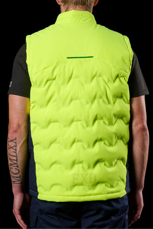 A person is shown from the back wearing the FXD WO-6 Hi Vis Insulated Puffer Vest over a black shirt, with arm tattoos and short blonde hair standing out against a black background.