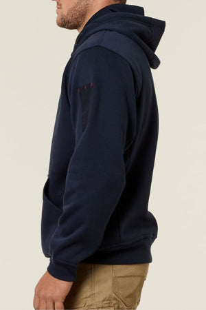 Against a plain background, someone is seen in profile wearing Hard Yakka's navy blue Plain Fleece Hoodie with beige pants. The hoodie has brushed fleece fabric and a sleeve pocket, with the hood down.