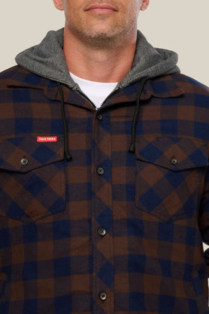 A man wears a blue and brown Hard Yakka Quilted Flannelette Shacket with front pockets and a small red tag on the left chest, over a gray hoodie. The photo is cropped at his nose and mid-torso.