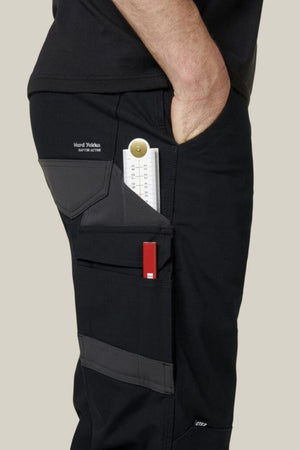 Wearing Hard Yakka Raptor Pant with Repreve ECO Ripstop, gray accents, this person has a folded ruler and red tool in side pockets, and their right hand rests in the front pocket.