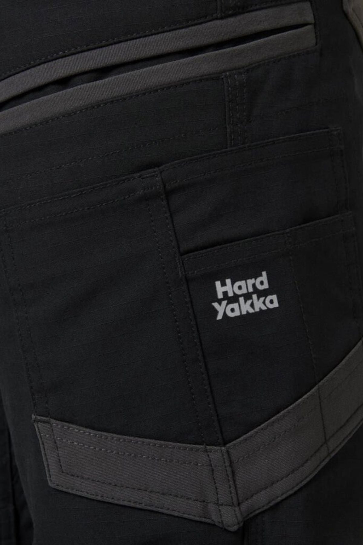 Close-up of dark-colored Hard Yakka Raptor Mid Short pocket with Active Fit stretch waistband for comfort, reinforced stitching, multiple pockets, and a prominent side pocket featuring the brand's logo.