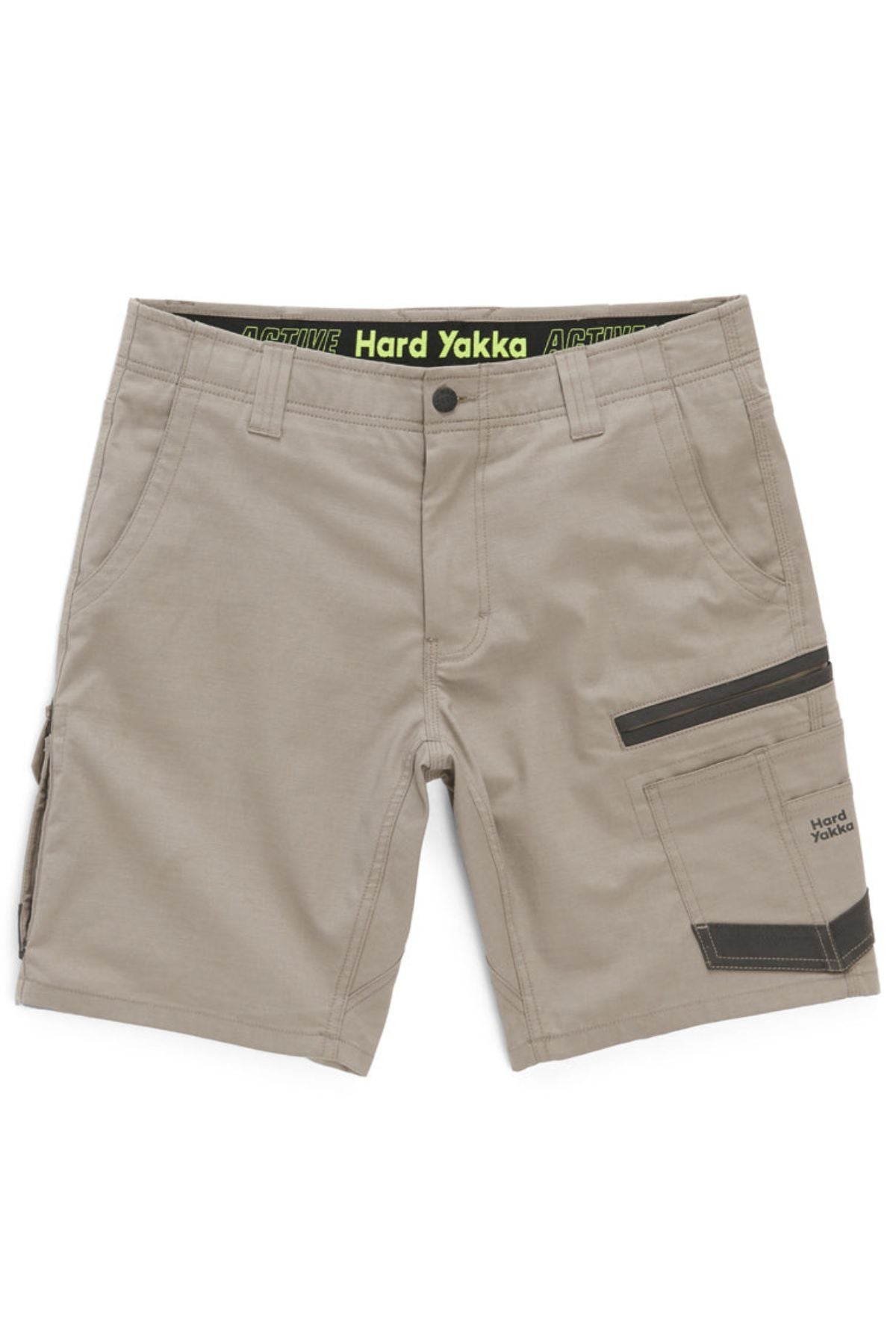The Hard Yakka Raptor Mid Short features a tan color and comes equipped with multiple pockets, including a black zippered pocket on the right side. It boasts an Active Fit stretch waistband with "Hard Yakka" text displayed on a black band. The design is clean and practical, making it ideal for manual labor or outdoor activities.