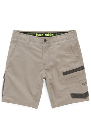 The Hard Yakka Raptor Mid Short features a tan color and comes equipped with multiple pockets, including a black zippered pocket on the right side. It boasts an Active Fit stretch waistband with "Hard Yakka" text displayed on a black band. The design is clean and practical, making it ideal for manual labor or outdoor activities.
