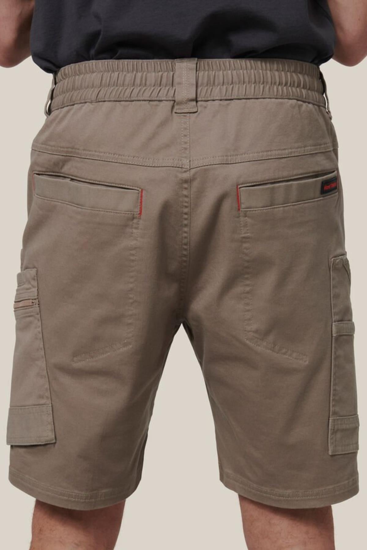 A person seen from the back wears Hard Yakka Tough Maxx Mid Shorts featuring an elastic waistband and multiple pockets, made from durable canvas, set against a plain background.
