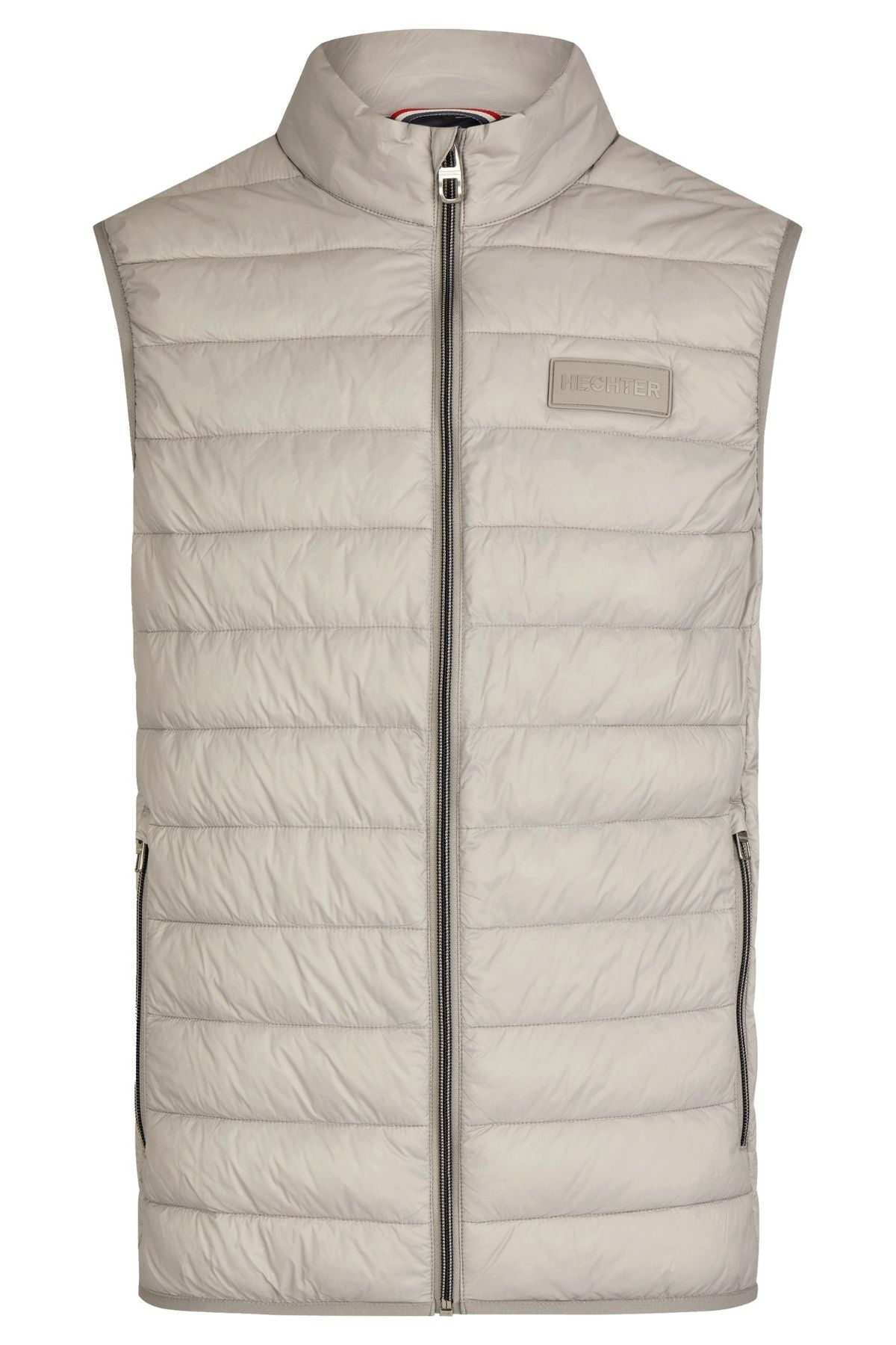 The Hechter Puffer Vest is a light gray, sleeveless nylon vest with a front zipper, two zippered side pockets for storage, a small rectangular logo patch on the left chest, and horizontal quilted stitching.