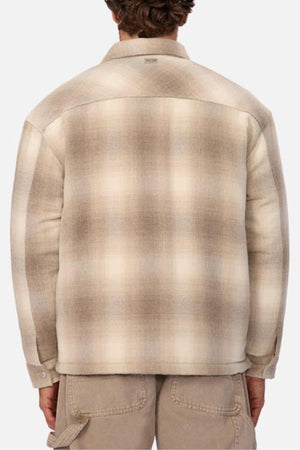 A person is shown from the back wearing the Industrie The Highland Jacket in beige and brown plaid with long sleeves and khaki pants. They appear ready for an adventure against a plain, light-colored background.