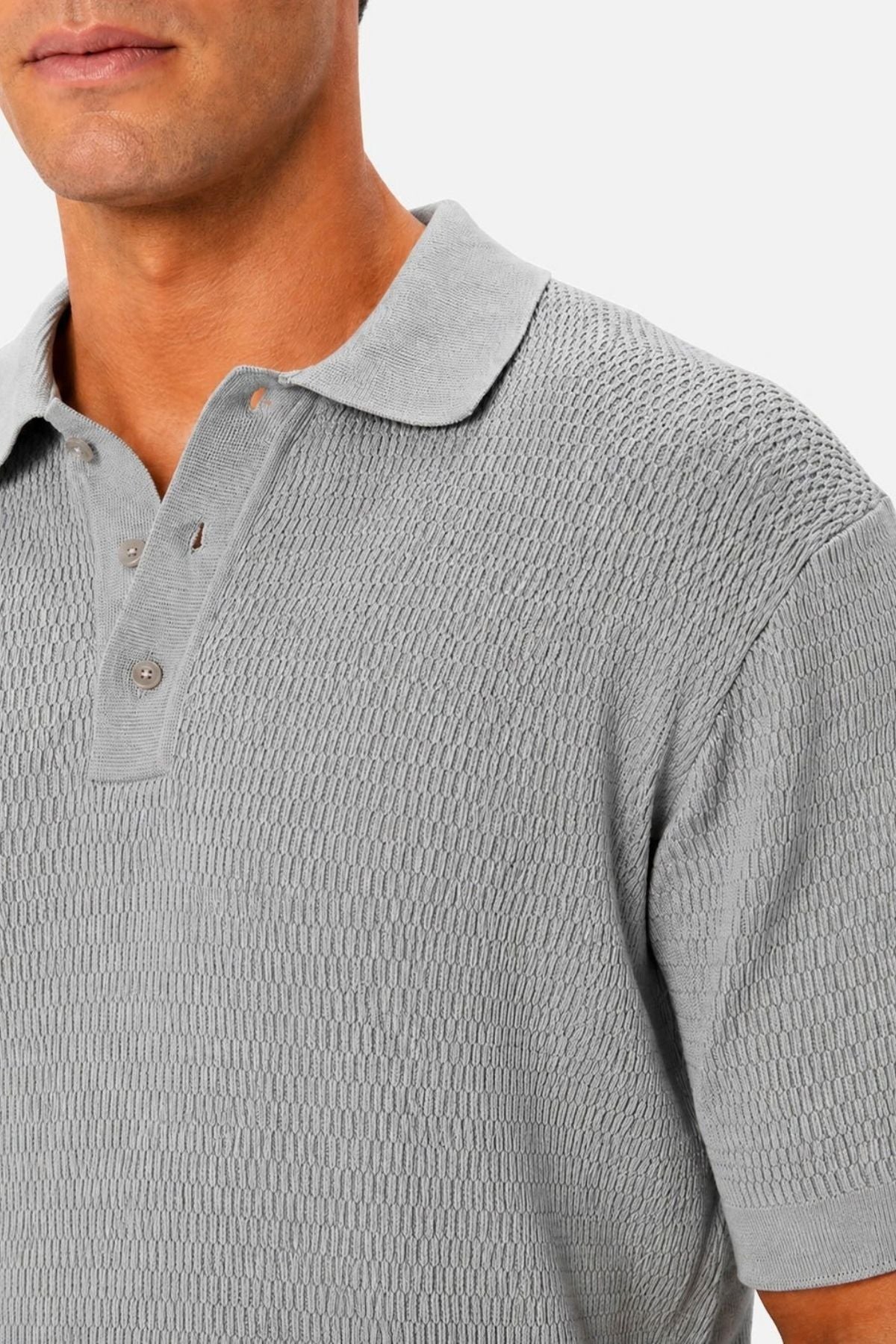 A man is wearing the Industrie The Bastien Polo, crafted from textured light gray fabric with a classic collar and three-button placket. The photo captures his upper torso and part of his face against a plain backdrop.