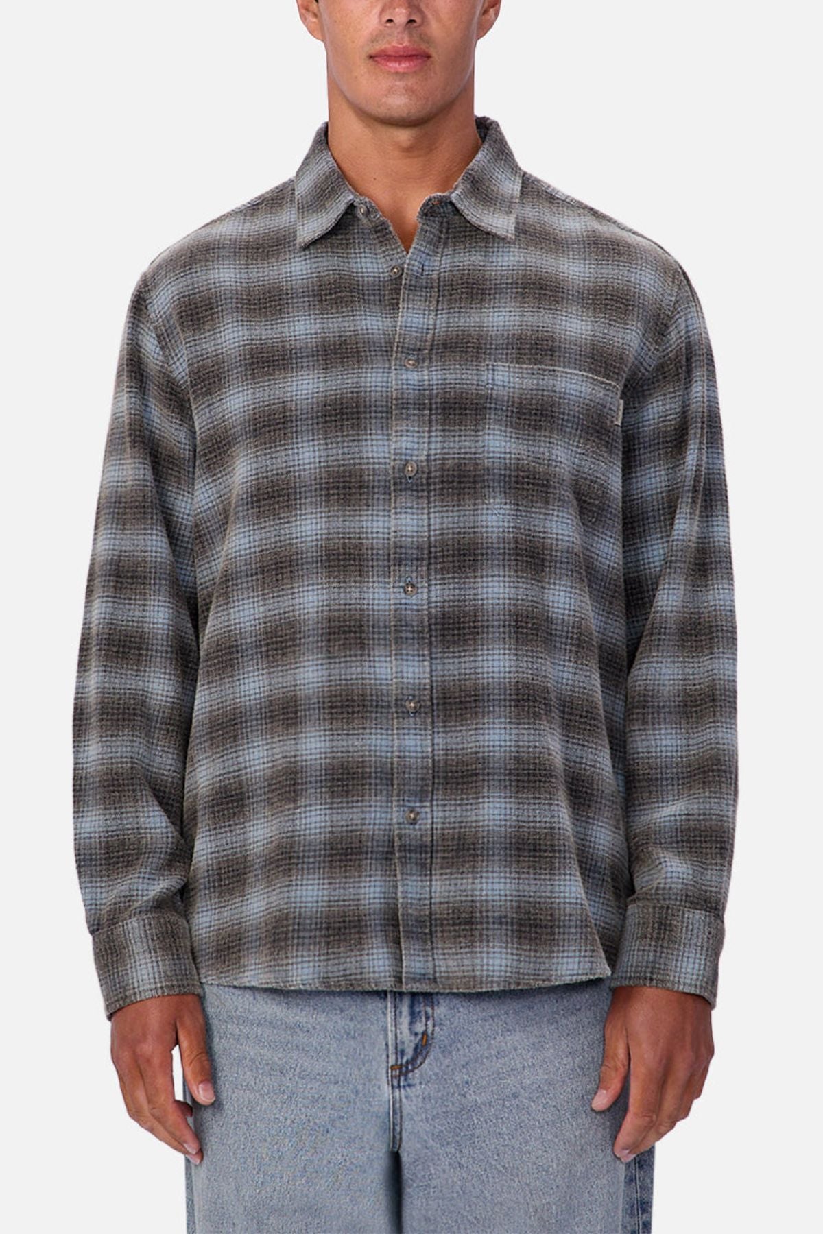 Someone wearing the Industrie Durango Long Sleeve Shirt, a grey and blue plaid cotton button-up, paired with light blue jeans, stands against a plain white background.