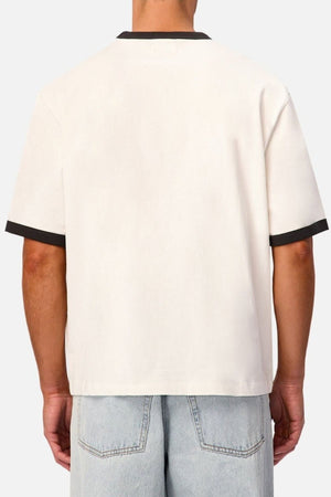 A person is shown from the back against a plain background, wearing the Industrie The Hudson Ringer Tee—a relaxed-fit, short-sleeve off-white shirt featuring black trim on the sleeves and a classic crew neck—paired with light blue denim jeans.