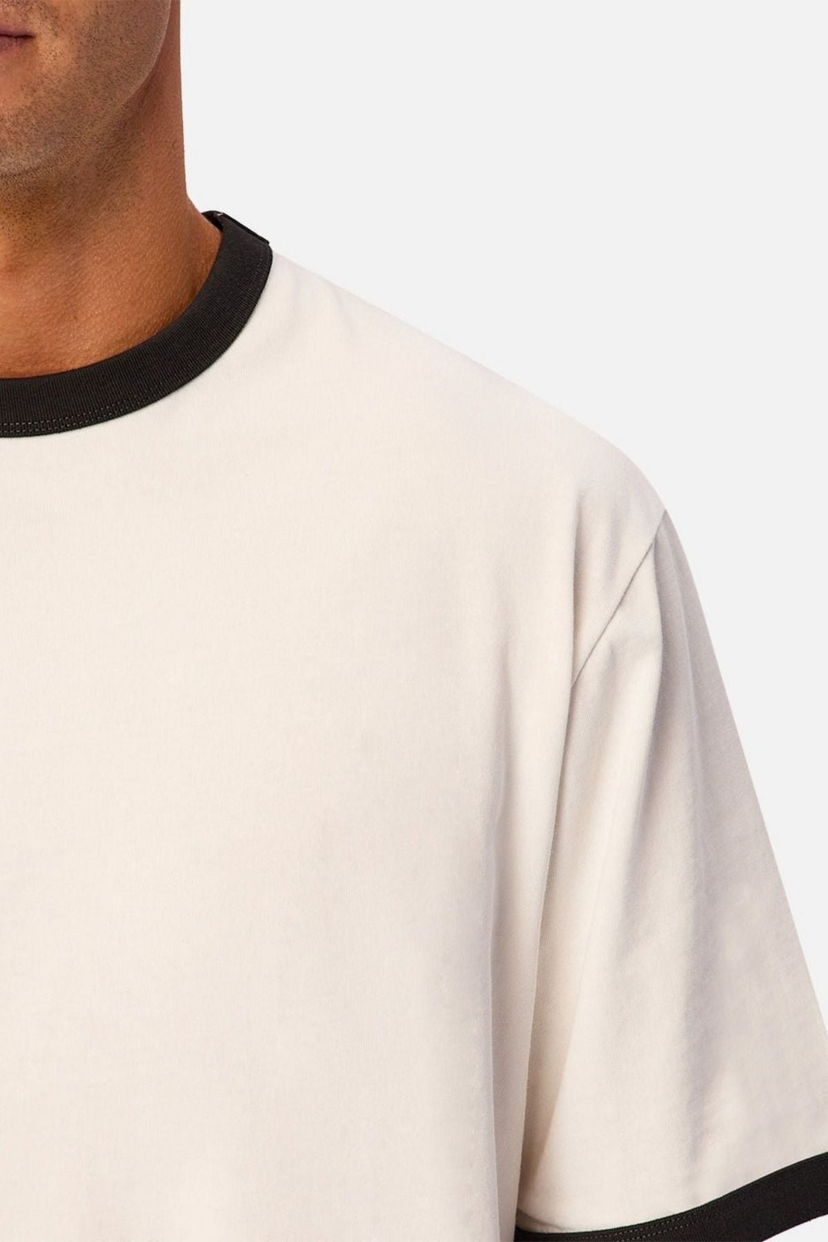 Close-up of a person wearing the Industrie The Hudson Ringer Tee, featuring classic black trim around the crew neck. Only part of the person’s face, neck, and shoulder are visible against a plain background.
