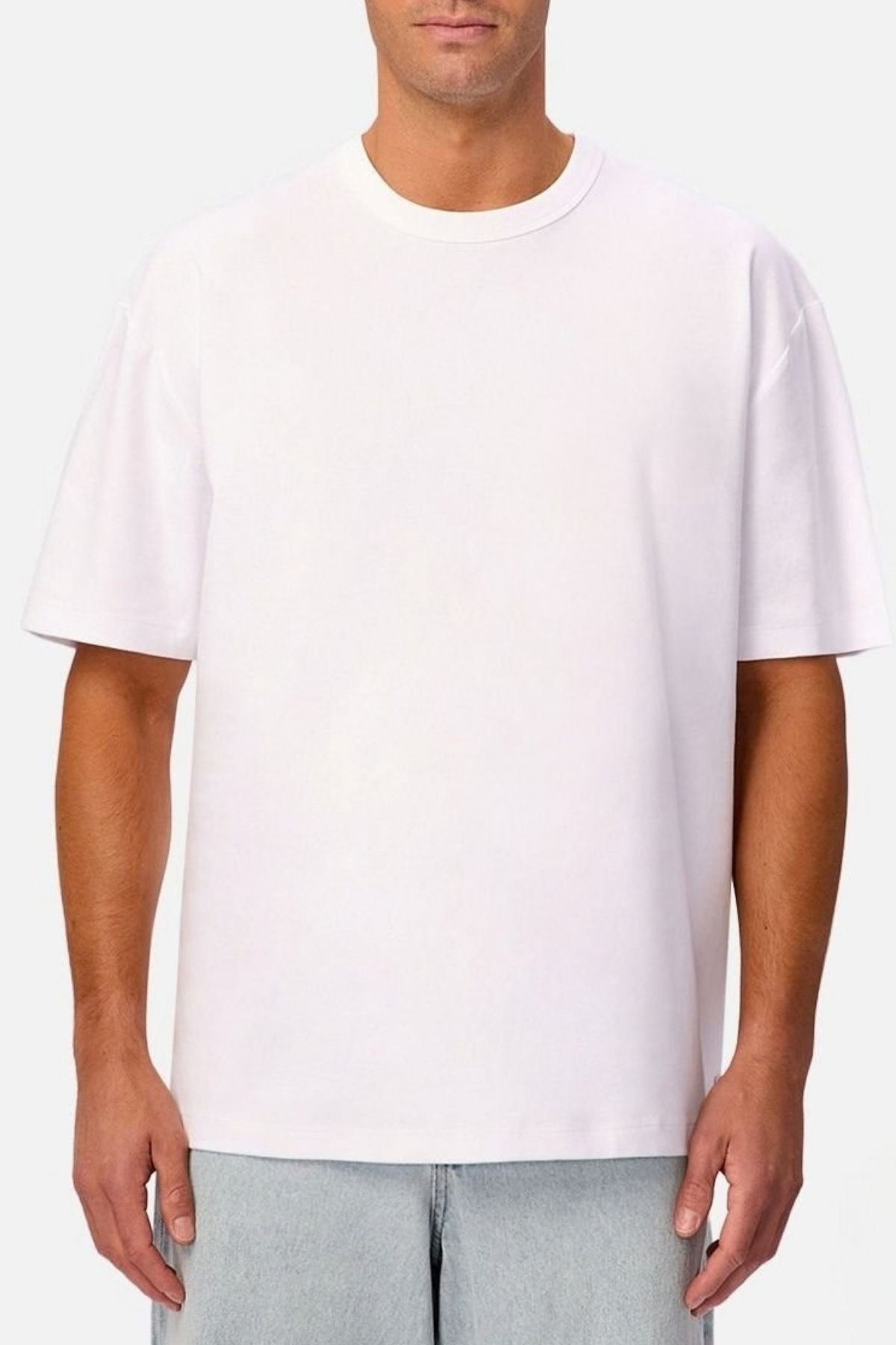 A man stands against a neutral background wearing the Industrie Luxe Del Sur Tee in plain white, crafted from 100% cotton, paired with light blue jeans.