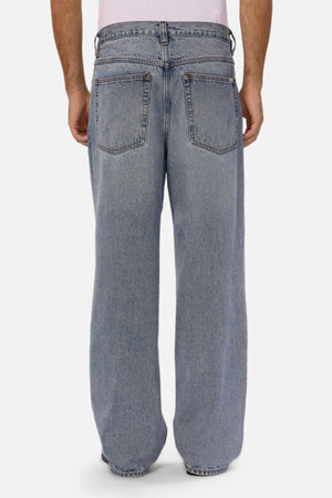 A person, shown from the waist down against a plain background, models Industrie The 80's Jeanโvintage-inspired, light blue relaxed fit jeans with large back pocketsโpaired with a white shirt.