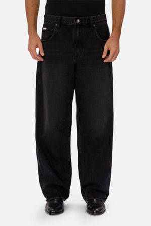 A person models the Industrie The 80's Jean—vintage-inspired, black durable denim—paired with black shoes, standing facing forward against a plain light gray background. Only the lower torso and legs are shown.