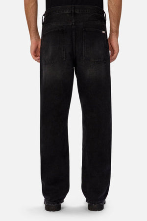 A person models Industrie The 90's Jean, vintage washed denim with a relaxed straight leg fit and two back pockets, crafted from 100% cotton, against a plain light background.