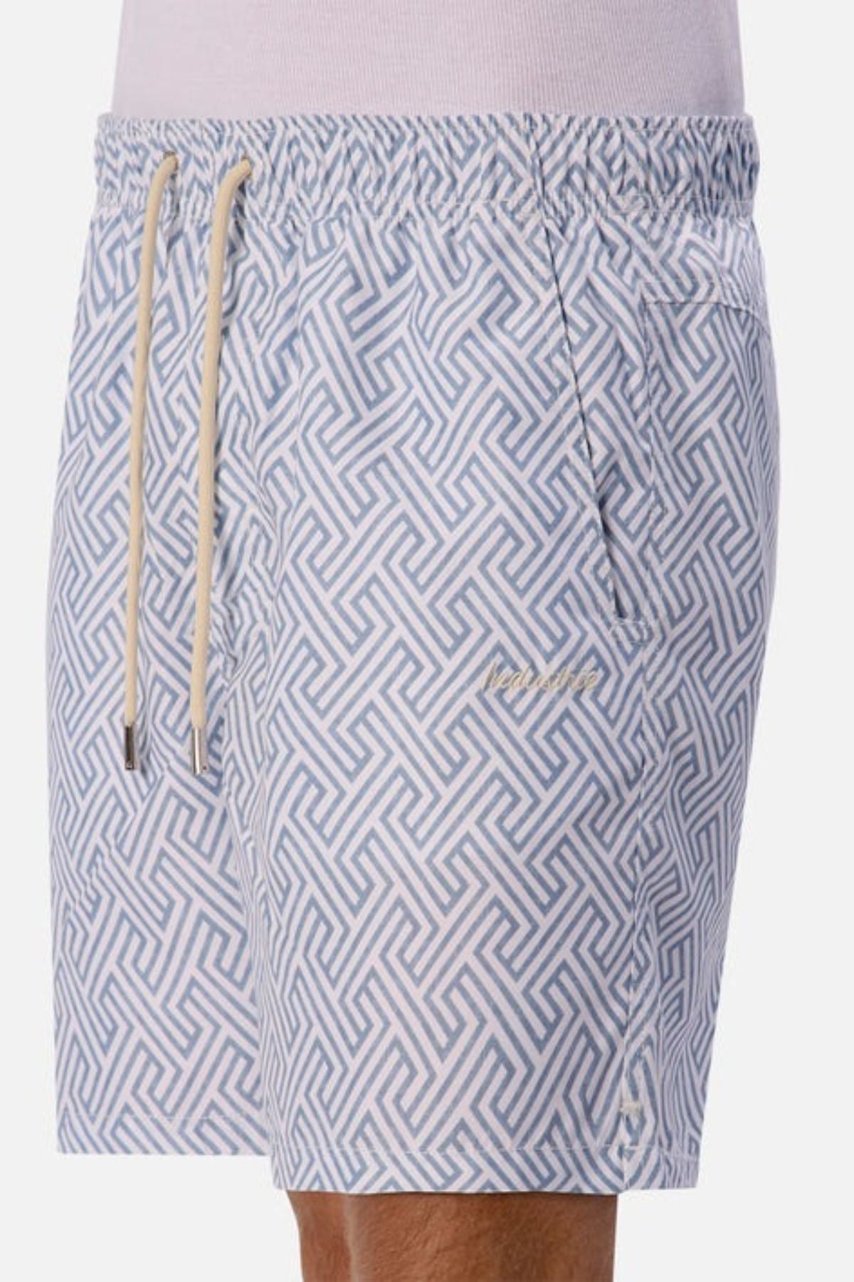 A man wears the Industrie The Alvarado Swim Short, featuring quick-drying patterned fabric in a blue and white geometric maze design. These swim shorts come with an elastic waistband, drawstring, and offer a tailored regular fit for effortless style.
