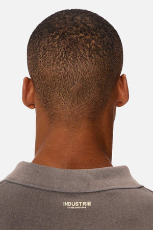 A close-up rear view of a person with short hair wearing the Industrie The Burbank Polo Track, a gray collared shirt featuring "INDUSTRIE" printed in white across the back.