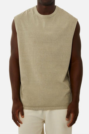 A person wearing the Industrie The Del Sur Sleeveless Tee, crafted from 100% cotton in a beige hue, stands against a plain background facing the camera. Their relaxed arms rest at their sides, enhancing the effortlessly chic appearance of their white pants and oversized fit.