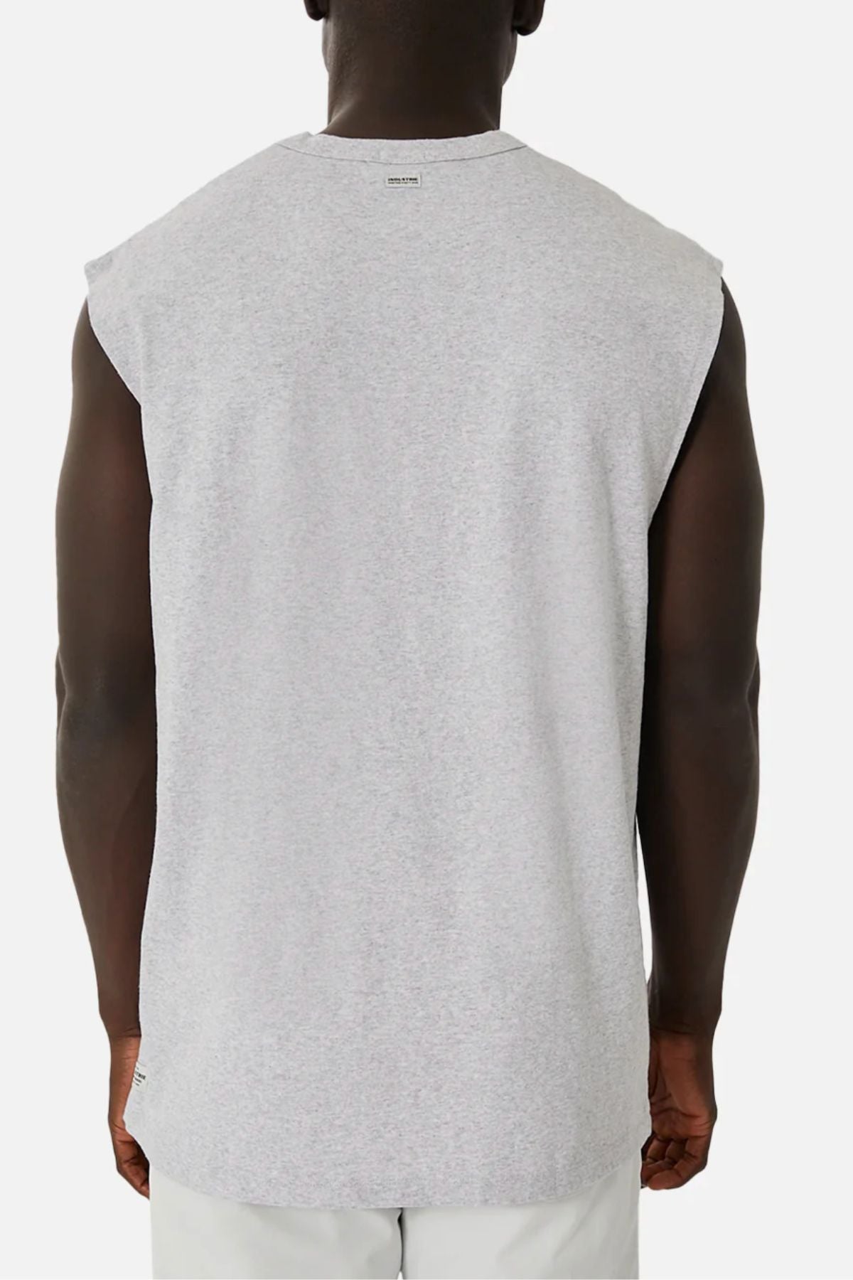 A person is shown from the back, wearing the Industrie The Del Sur Sleeveless Tee in light gray with an oversized fit and light-colored pants. The shirt drapes loosely against a plain white background.