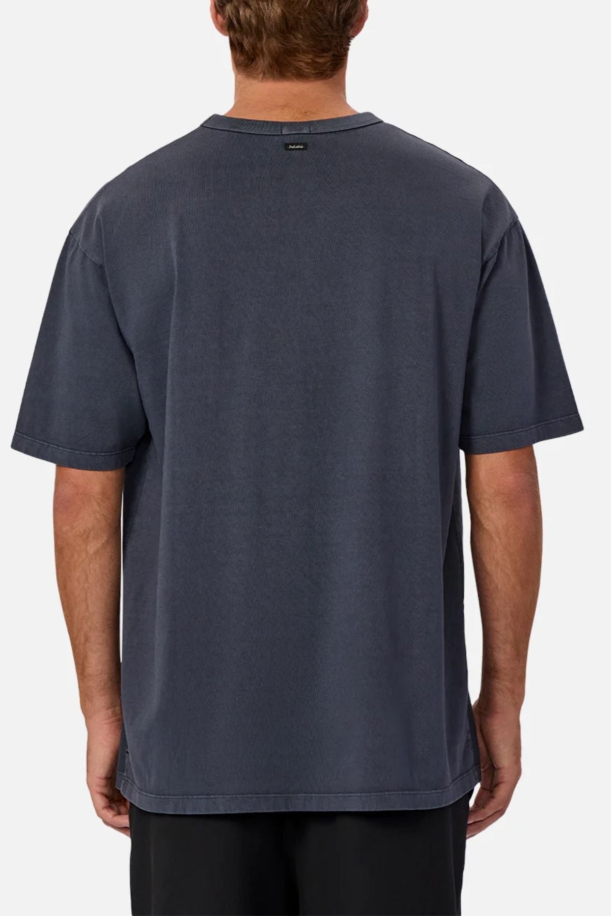 A person seen from behind wears an oversized, short-sleeve dark gray Industrie The Del Sur Tee and black shorts, standing against a plain light gray background.