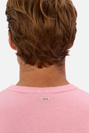Rear view of a person with light brown hair wearing an oversized pink sweater labeled "Industrie The Del Sur Tee" on the back, crafted in heavyweight fabric. The background is plain white.