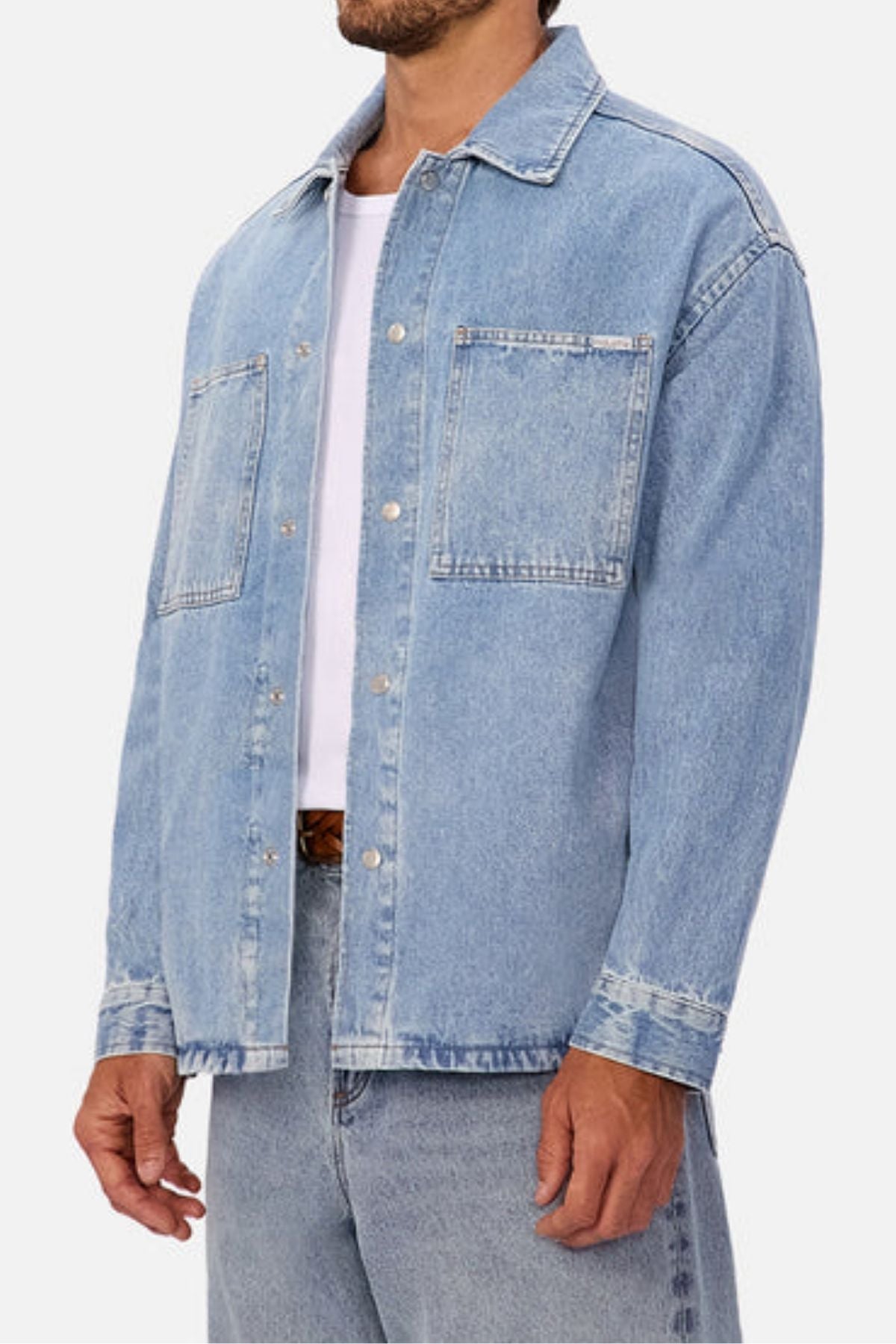 A man wears the Industrie The Denim Overshirt in light blue over a white t-shirt with matching relaxed-fit jeans, standing against a plain background for a laid-back vintage look.