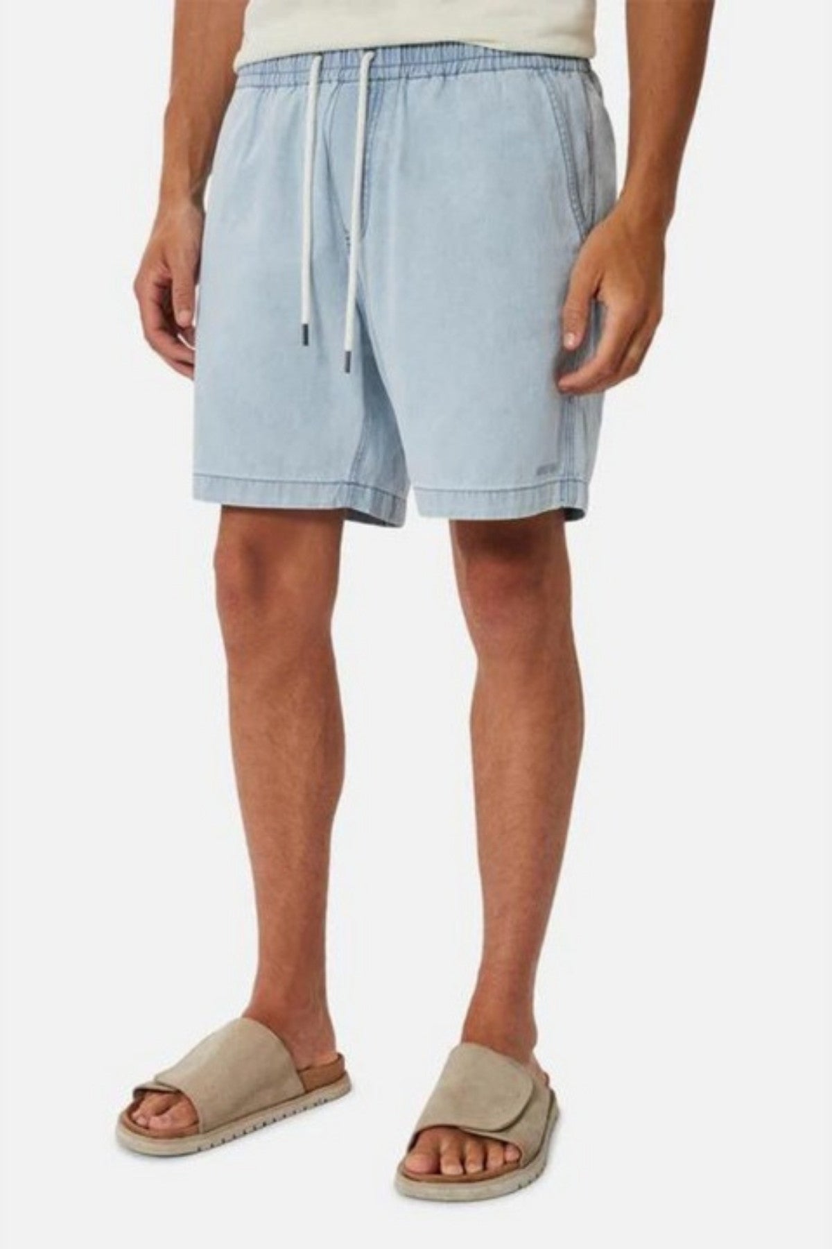 A person is dressed in a casual outfit comprising Industrie The Dublin Short in light blue, featuring an elasticised waistband, paired with a white top and beige slide sandals. This ensemble provides a breathable fit against the plain white background.