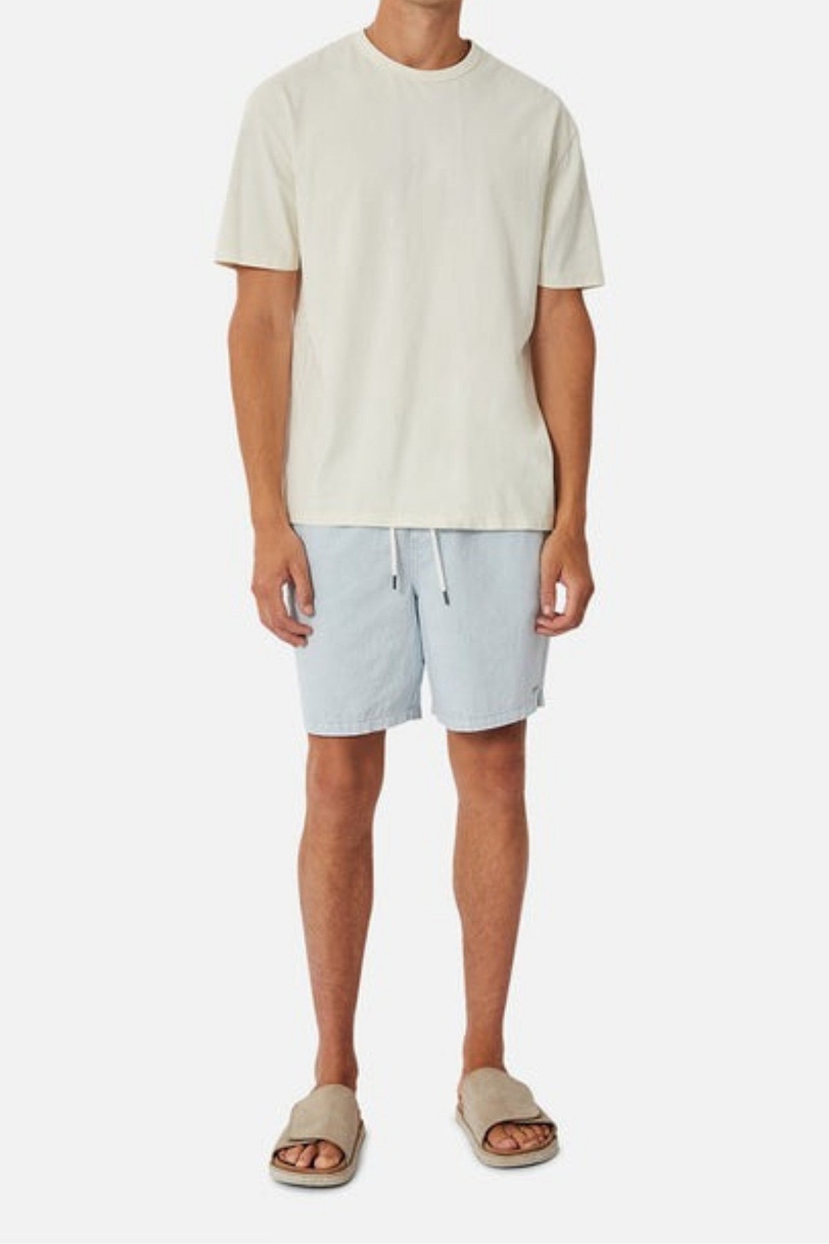 A person is dressed in a plain white T-shirt and Industrie The Dublin Short in light blue, which provides a comfortable and breathable fit with its elasticised waistband. They complete the look with beige slides while standing against a plain white background.