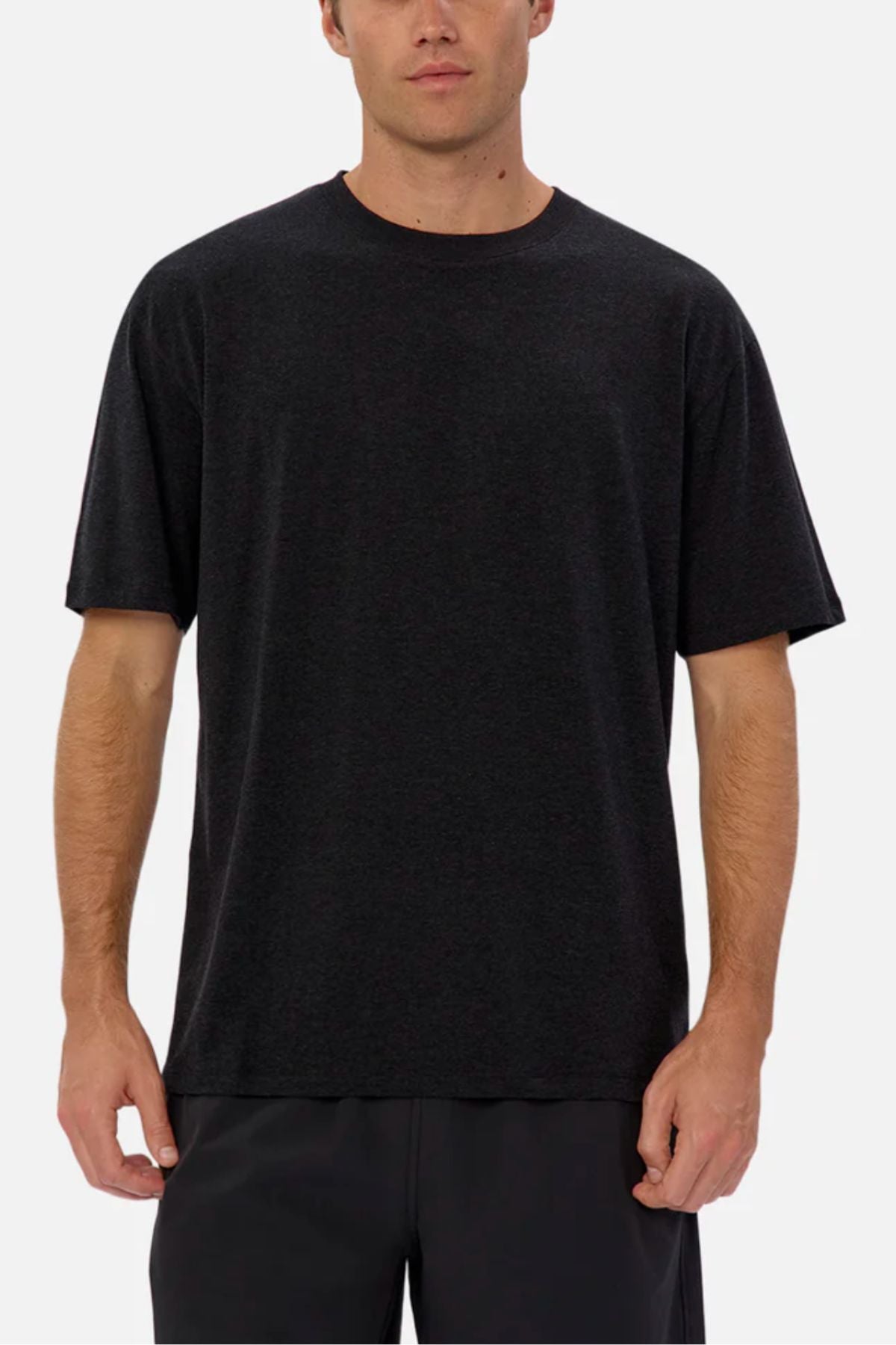 A man wears the Industrie The Freeman Athletic Tee—relaxed fit, short-sleeve, black—with dark pants, standing facing forward against a plain light background.