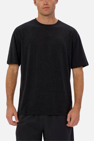A man wears the Industrie The Freeman Athletic Tee—relaxed fit, short-sleeve, black—with dark pants, standing facing forward against a plain light background.