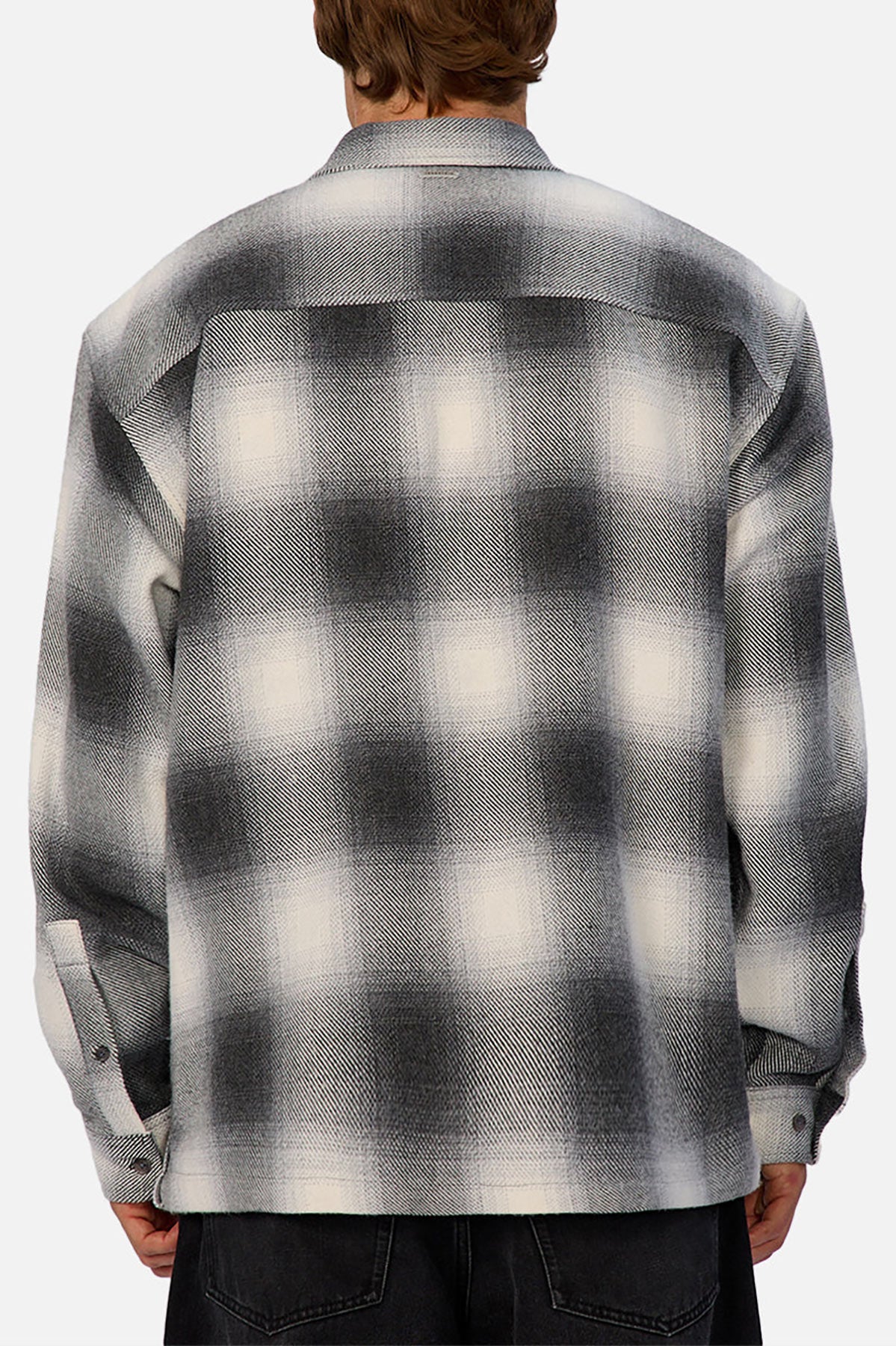 A person is shown from behind wearing the Industrie The Highland Shirt in black, white, and gray with long sleeves, dark pants, a relaxed fit, and a subtle shadow check pattern for effortless style.