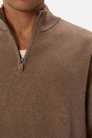 A close-up of a person wearing the Industrie The Lakewood Zip Neck Knit in light brown over a white shirt, zipper partially open, against a plain light background.