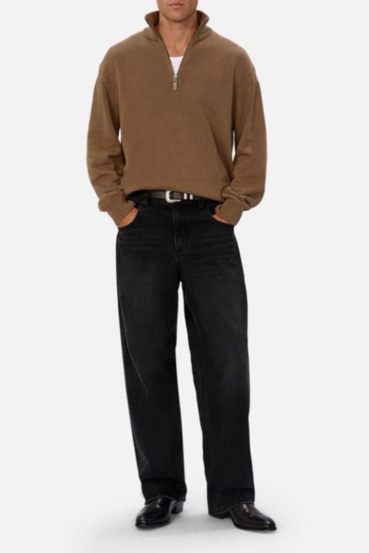 Wearing the Industrie The Maine Zip Neck Knit in regular fit over a white shirt, paired with black jeans and black shoes, a person stands hands-in-pockets against a light background.