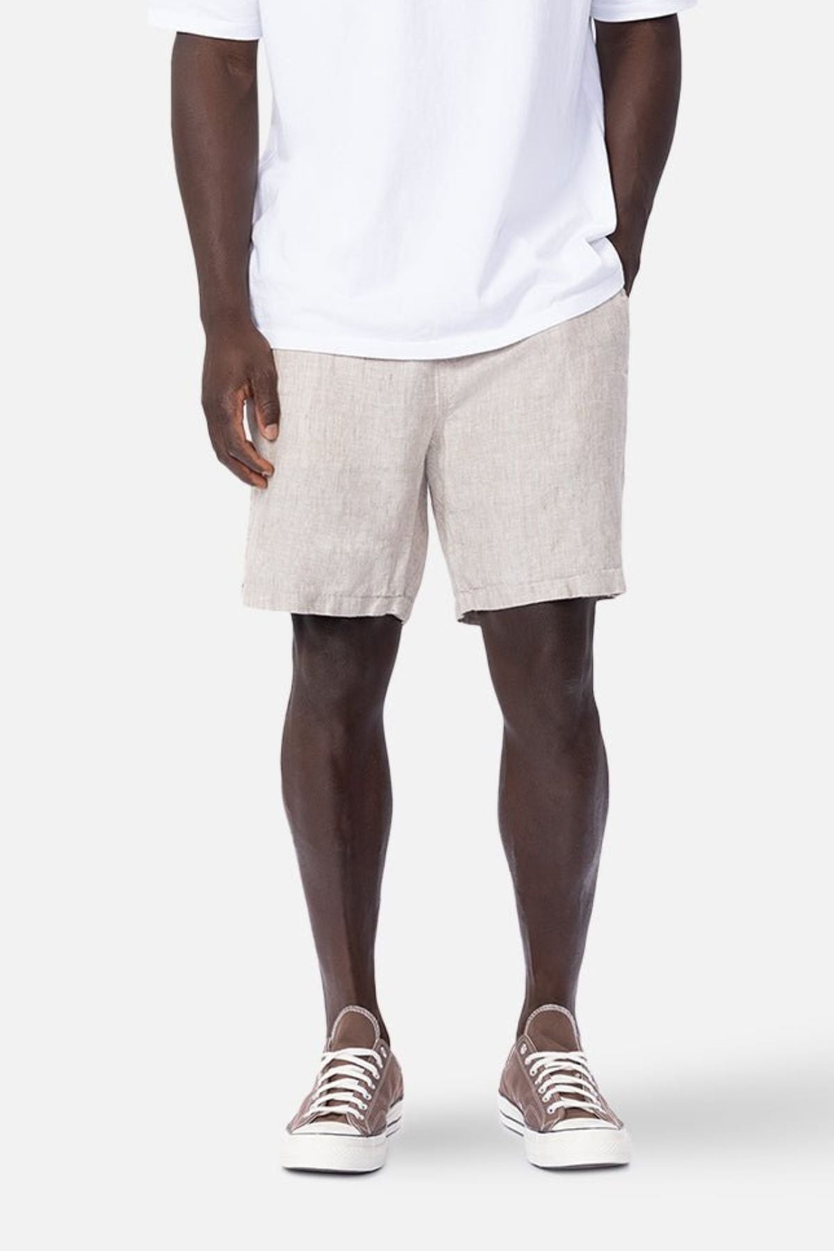 A person wearing a white t-shirt, Industrie The Marina Linen Short in beige, and brown sneakers.