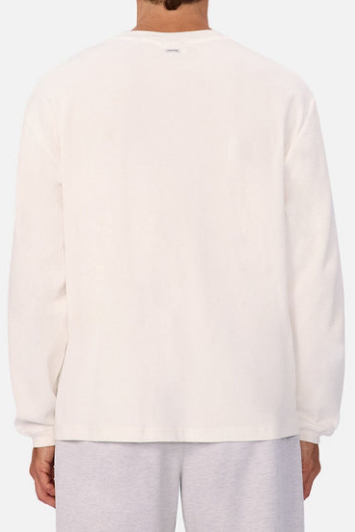 A person is seen from the back wearing Industrie The Marlon Long Sleeve Tee, crafted from 100% cotton textured fabric, and light gray pants, set against a light background.