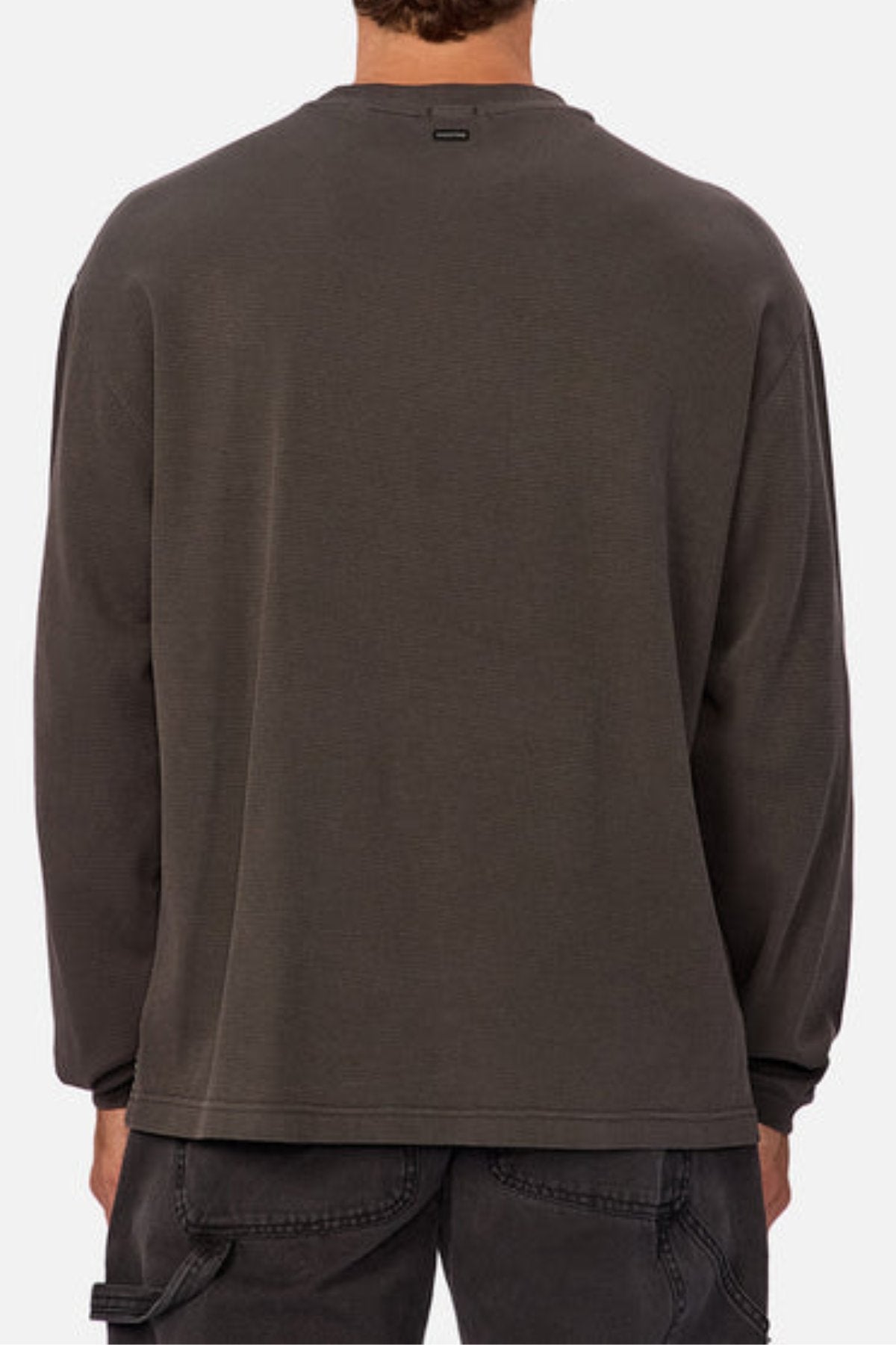 A person shown from the back wears a loose-fitting, long-sleeve, dark gray Industrie The Marlon Long Sleeve Tee in textured fabric with black jeans against a plain light background.