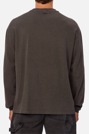 A person shown from the back wears a loose-fitting, long-sleeve, dark gray Industrie The Marlon Long Sleeve Tee in textured fabric with black jeans against a plain light background.