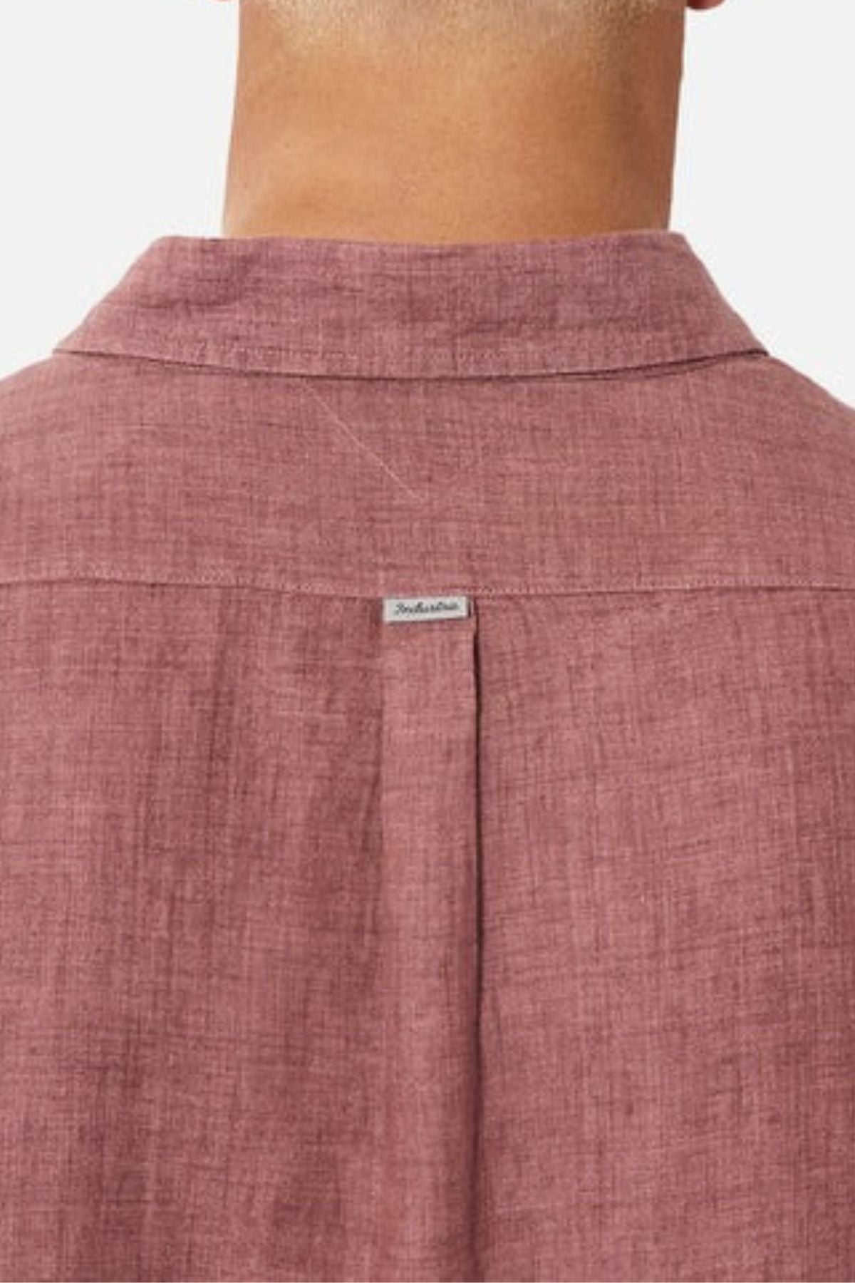 The image depicts the back view of an individual dressed in a reddish-brown shirt from Industrie, specifically "The Midland Shirt." A small label with the INDUSTRIE branding is visible near the top center of the shirt, and the fabric exhibits a textured appearance.