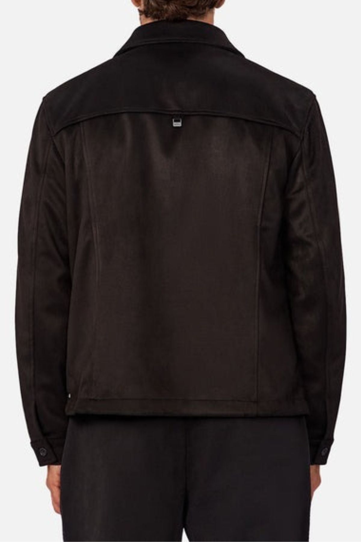A person is seen from the back wearing the Industrie The Monaco Jacket in black, featuring a collar, long lined sleeves, a lined torso, and a small rectangular tag at the upper back, paired with black pants for a stylish look.