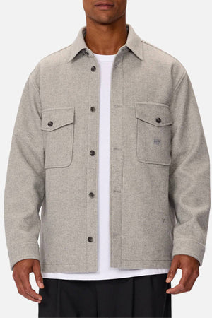 A man wearing the Industrie The New Coleman Jacket—relaxed fit, classic collar, two chest pockets—over a white t-shirt stands against a plain background.