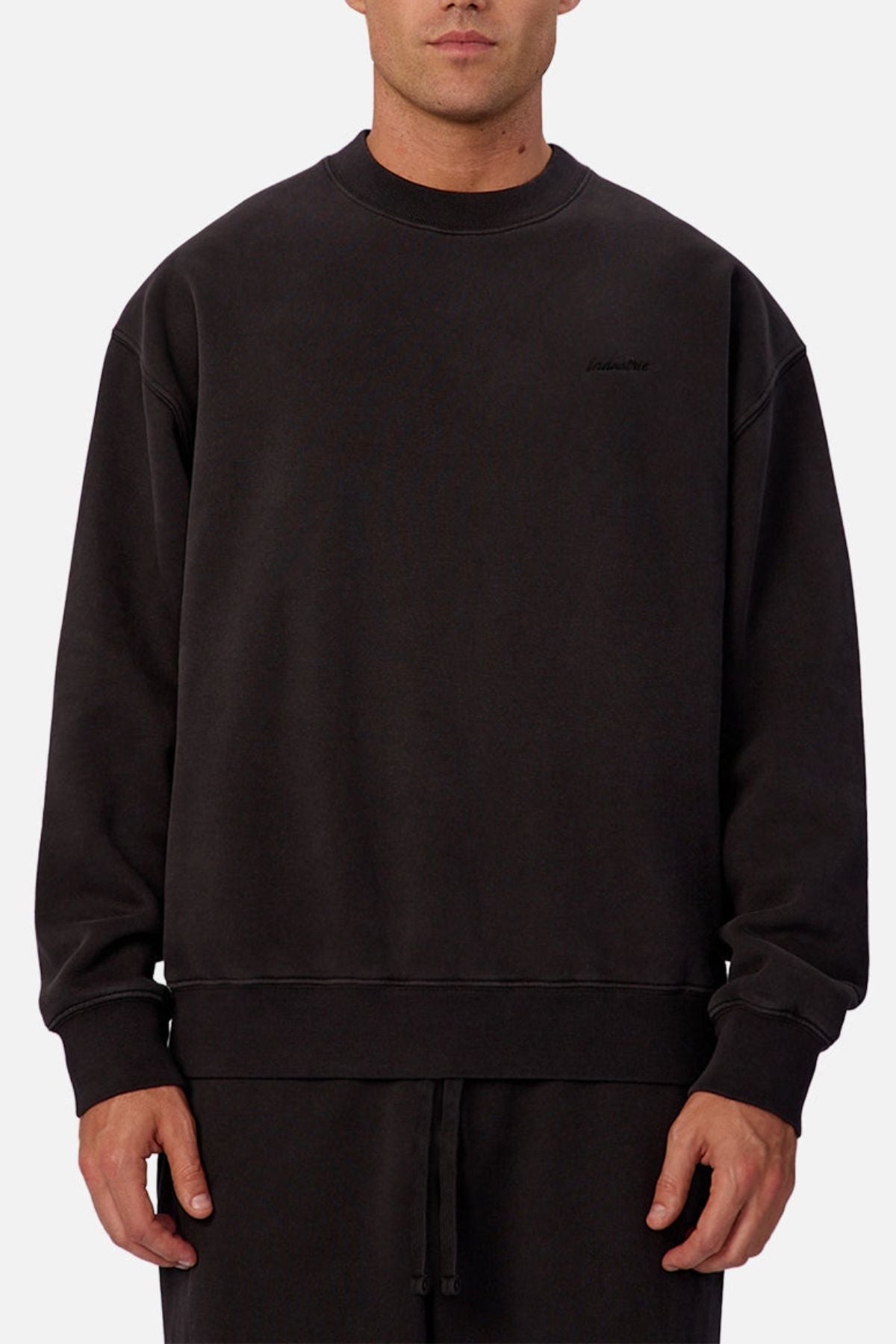 A man wears the Industrie The New Del Sur Sweatshirt, showcasing its premium build and subtle stitching, paired with matching black pants against a plain light gray background.