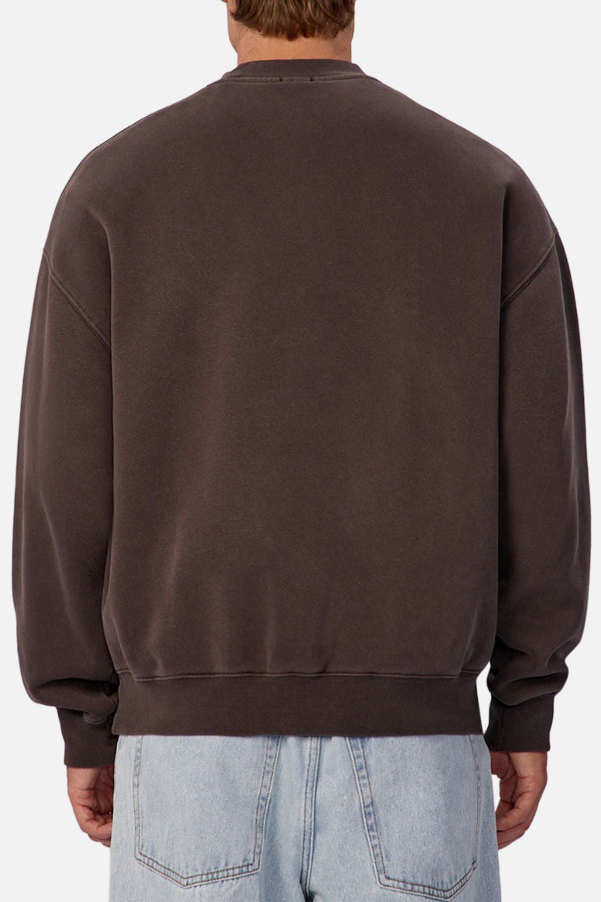 A person is shown from the back wearing the Industrie The New Del Sur Sweatshirt in dark brown with a loose, oversized fit, paired with light blue jeans against a plain background.