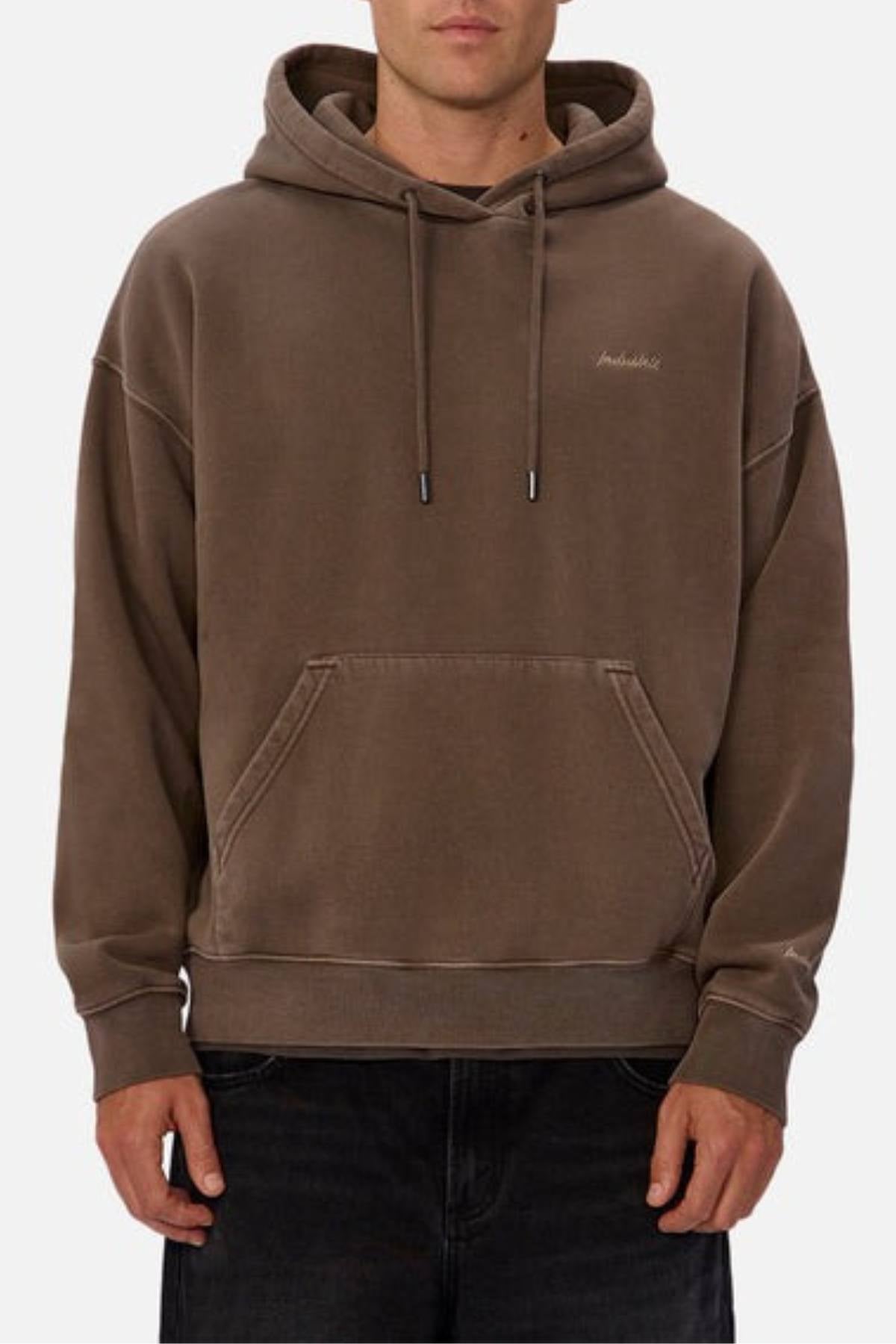 A person wearing the Industrie The New Del Sur Washed Hoodie in brown, featuring an oversized fit, front pocket, and drawstrings, paired with dark pants. Only the torso is visible.