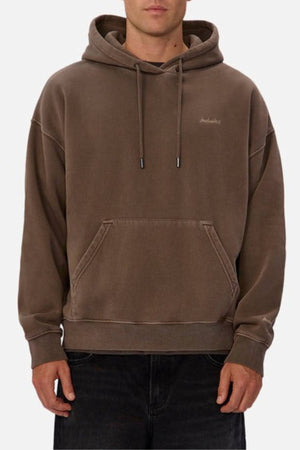 A person wearing the Industrie The New Del Sur Washed Hoodie in brown, featuring an oversized fit, front pocket, and drawstrings, paired with dark pants. Only the torso is visible.