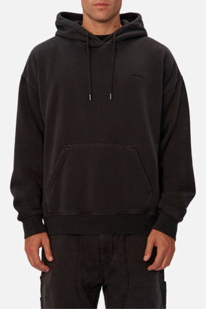 Someone wearing the Industrie The New Del Sur Washed Hoodie, featuring an oversized fit with drawstrings and a front kangaroo pocket, pairs it with black pants against a plain light background.