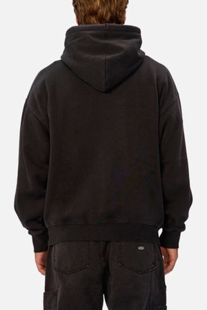 A person with short light brown hair is seen from behind wearing an oversized Industrie The New Del Sur Washed Hoodie and black jeans, standing against a plain light background.