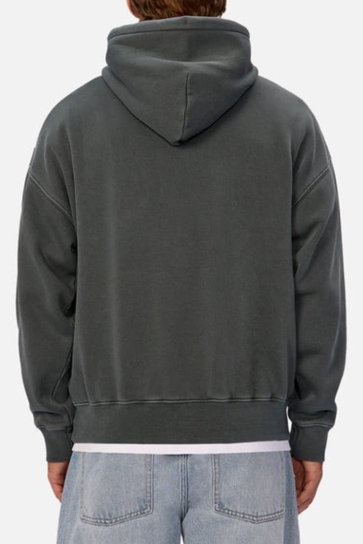 A person is seen from the back wearing the Industrie The New Del Sur Washed Hoodie in dark gray, styled with light blue jeans and a white shirt underneath. The hood is up, and the background is plain and light-colored.