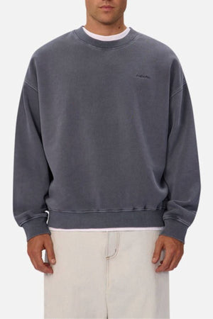A person wears the oversized Industrie The New Del Sur Washed Sweat in faded gray with a subtle chest logo and light-colored pants, standing against a plain background.