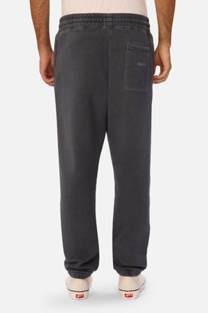 A person is seen from the back wearing Industrie The New Del Sur Washed Trackpant in dark gray with an oversized fit, single back pocket, elastic waistband and cuffs, paired with white sneakers against a plain white background.